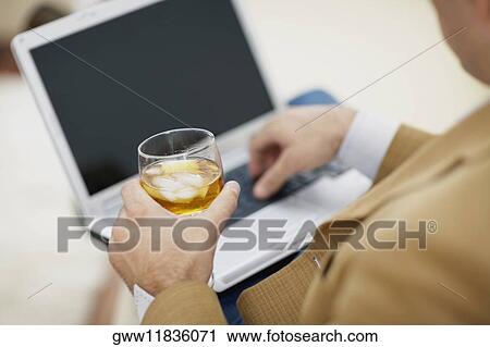 Mid section view of a man using a laptop and holding a glass of wine View Large Photo Image Stock Image - Mid section view of a man using a laptop and holding a glass of wine. Fotosearch