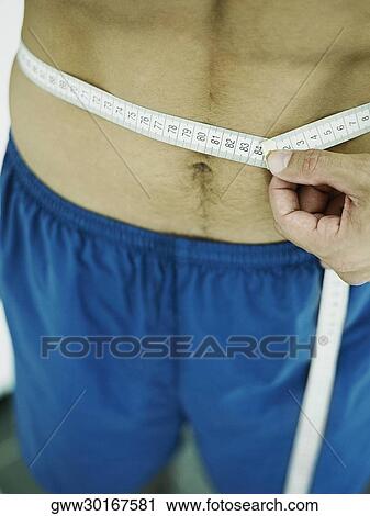 Mid section view of a person measuring his waist with a tape measure View Large Photo Image Stock Image - Mid section view of a person measuring his waist with a tape measure. Fotosearch