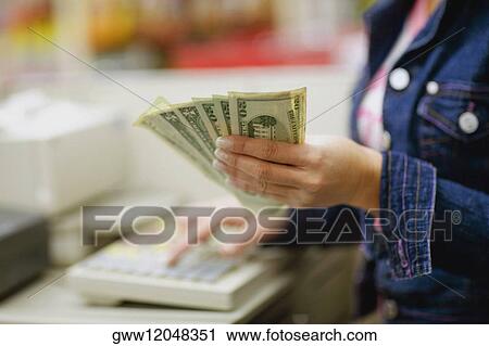 Mid section view of a sales clerk holding paper currency in a checkout counter View Large Photo Image Stock Image - Mid section view of a sales clerk holding paper currency in a checkout counter. Fotosearch