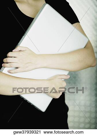Mid section view of a woman carrying a laptop View Large Photo Image Stock Image - Mid section view of a woman carrying a laptop. Fotosearch