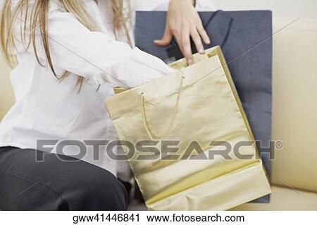 Mid section view of a woman sitting with shopping bags View Large Photo Image Stock Image - Mid section view of a woman sitting with shopping bags. Fotosearch