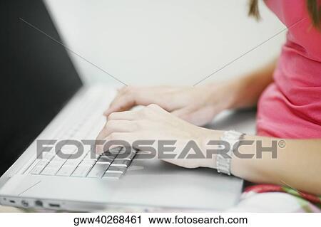Stock Image - Mid section view of a woman using a laptop. Fotosearch