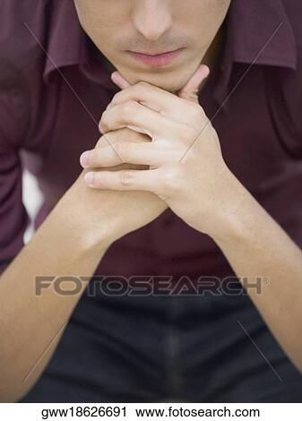 Stock Image - Mid section view of a young man with his hands on his chain. Fotosearch