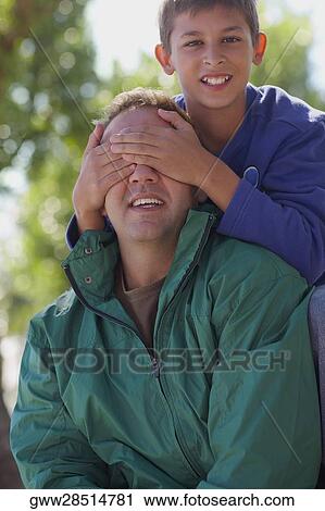 Portrait of a boy closing his father's eye View Large Photo Image Stock Image - Portrait of a boy closing his father's eye. Fotosearch