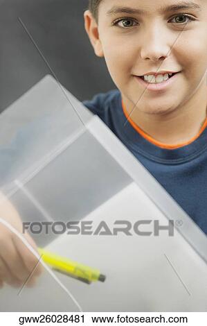Stock Image - Portrait of a boy holding a pen and a folder. Fotosearch