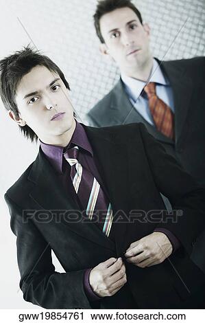 Portrait of a businessman buttoning his coat with another businessman standing behind him View Large Photo Image Stock Image - Portrait of a businessman buttoning his coat with another businessman standing behind him. Fotosearch