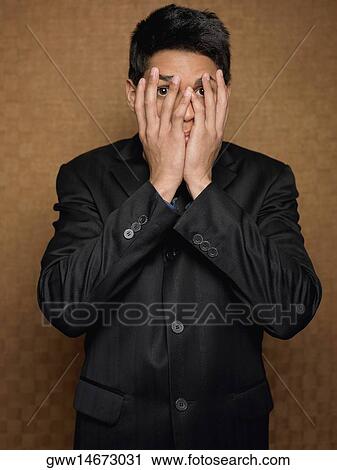 Stock Image - Portrait of a businessman covering his mouth with his hands. Fotosearch
