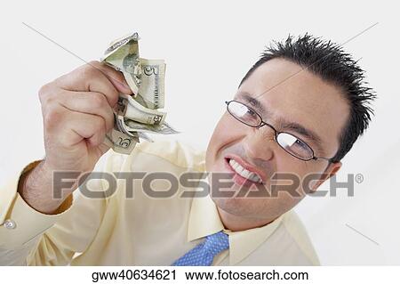 Stock Image - Portrait of a businessman crushing five dollar bills. Fotosearch