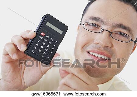 Stock Image - Portrait of a businessman holding a calculator and a coin. Fotosearch