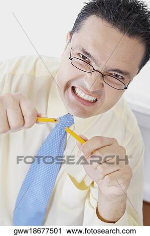 Stock Image - Portrait of a businessman holding broken pieces of a pencil. Fotosearch