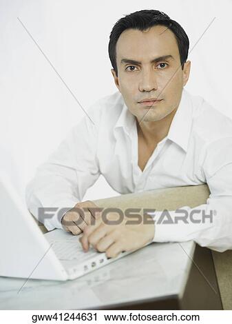 Portrait of a businessman in front of a laptop View Large Photo Image Stock Image - Portrait of a businessman in front of a laptop. Fotosearch