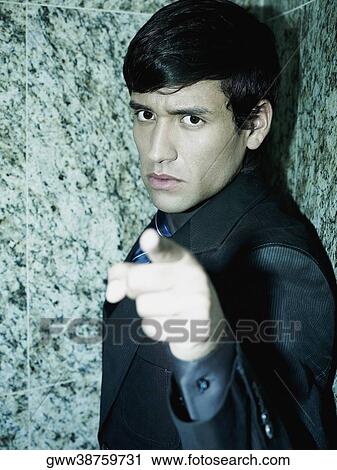 Stock Image - Portrait of a businessman pointing forward. Fotosearch