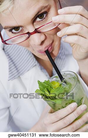 Stock Image - Portrait of a businesswoman drinking a glass of mint julep. Fotosearch
