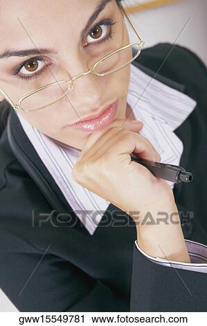 Stock Image - Portrait of a businesswoman holding a pen and thinking. Fotosearch
