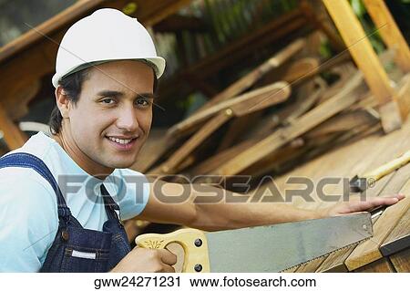Portrait of a carpenter cutting a plank with a saw View Large Photo Image Stock Image - Portrait of a carpenter cutting a plank with a saw. Fotosearch