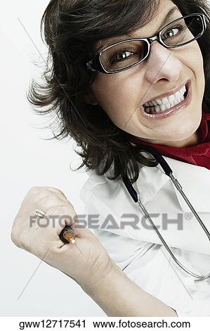 Portrait of a female doctor holding a syringe and clenching her teeth View Large Photo Image Stock Image - Portrait of a female doctor holding a syringe and clenching her teeth. Fotosearch