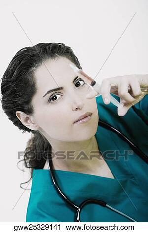 Stock Image - Portrait of a female doctor holding a syringe. Fotosearch