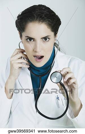 Stock Image - Portrait of a female doctor holding a stethoscope and making a face. Fotosearch