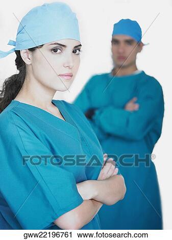 Portrait of a female doctor standing with her arms crossed and a male doctor standing in the background View Large Photo Image Stock Image - Portrait of a female doctor standing with her arms crossed and a male doctor standing in the background. Fotosearch