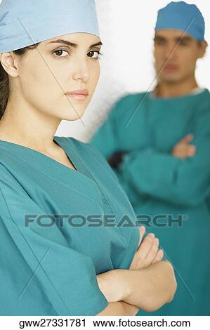 Portrait of a female doctor standing with her arms crossed and a male doctor standing in the background View Large Photo Image Stock Image - Portrait of a female doctor standing with her arms crossed and a male doctor standing in the background. Fotosearch