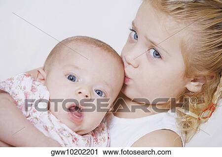 Portrait of a girl kissing her sister View Large Photo Image Stock Image - Portrait of a girl kissing her sister. Fotosearch