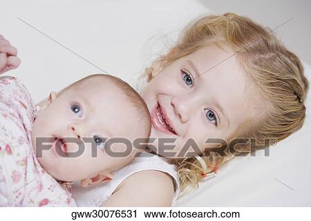 Portrait of a girl smiling with her sister View Large Photo Image Stock Image - Portrait of a girl smiling with her sister. Fotosearch