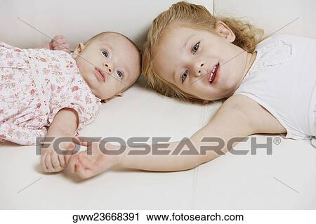 Portrait of a girl with her sister lying on the bed View Large Photo Image Stock Image - Portrait of a girl with her sister lying on the bed. Fotosearch