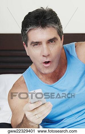 Portrait of a mature man holding a remote control View Large Photo Image Stock Image - Portrait of a mature man holding a remote control. Fotosearch