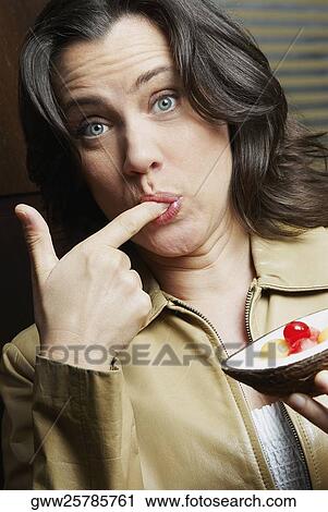 Portrait of a mature woman with her finger in her mouth and holding a tart View Large Photo Image Stock Image - Portrait of a mature woman with her finger in her mouth and holding a tart. Fotosearch