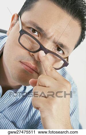 Stock Image - Portrait of a mid adult man adjusting his eyeglasses. Fotosearch