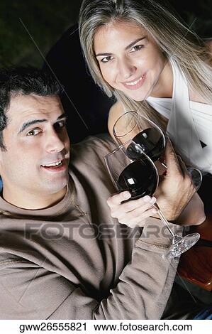 Portrait of a mid adult man and a mid adult woman holding glasses of red wine and smiling View Large Photo Image Stock Image - Portrait of a mid adult man and a mid adult woman holding glasses of red wine and smiling. Fotosearch
