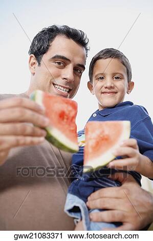 Portrait of a mid adult man carrying his son and holding slices of watermelon View Large Photo Image Stock Image - Portrait of a mid adult man carrying his son and holding slices of watermelon. Fotosearch