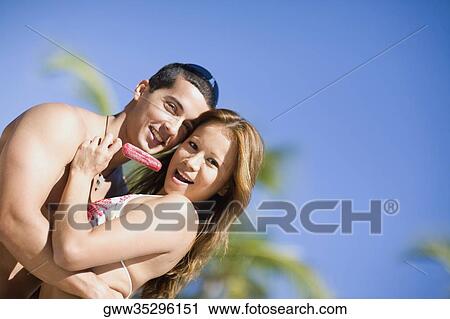Portrait of a mid adult man embracing a young woman holding an ice-cream View Large Photo Image Stock Image - Portrait of a mid adult man embracing a young woman holding an ice-cream. Fotosearch