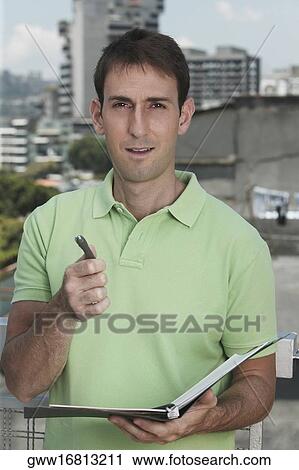 Stock Image - Portrait of a mid adult man holding a pen and a file. Fotosearch