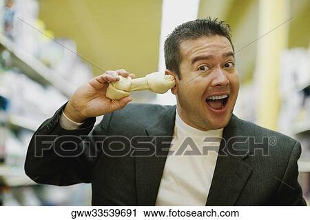 Stock Image - Portrait of a mid adult man holding a dog bone and shouting. Fotosearch