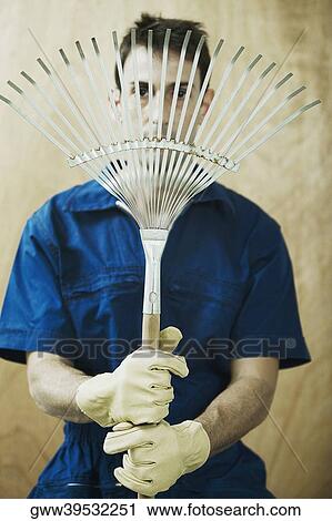 Portrait of a mid adult man holding a rake in front of his face View Large Photo Image Stock Image - Portrait of a mid adult man holding a rake in front of his face. Fotosearch