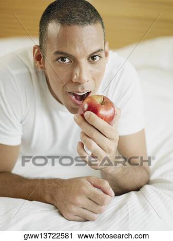 Portrait of a mid adult man lying on the bed and holding an apple View Large Photo Image Stock Image - Portrait of a mid adult man lying on the bed and holding an apple. Fotosearch
