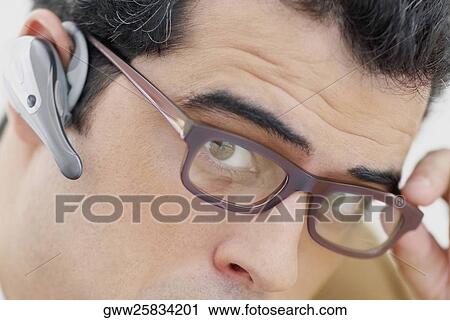 Stock Image - Portrait of a mid adult man wearing hands free device. Fotosearch
