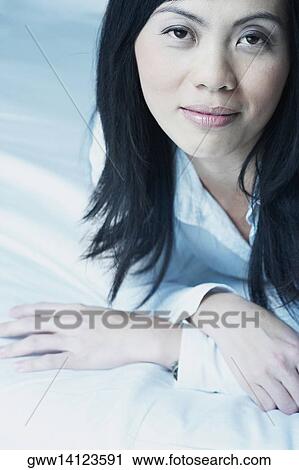Stock Image - Portrait of a mid adult woman lying on the bed. Fotosearch
