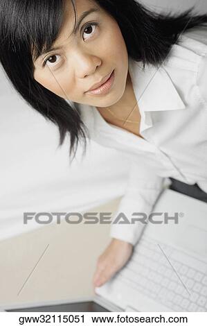 Stock Image - Portrait of a mid adult woman using a laptop. Fotosearch