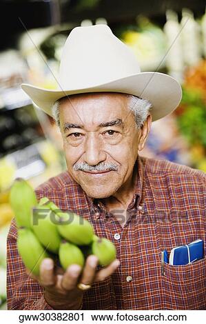 Portrait of a senior man holding a bunch of bananas View Large Photo Image Stock Image - Portrait of a senior man holding a bunch of bananas. Fotosearch