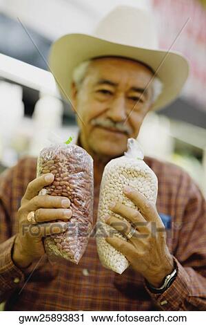Stock Image - Portrait of a senior man holding packets of cereals and smiling. Fotosearch