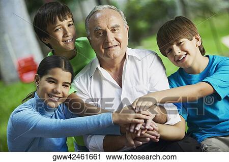 Portrait of a senior man with his grandchildren with their hands on top of the other View Large Photo Image Stock Image - Portrait of a senior man with his grandchildren with their hands on top of the other. Fotosearch