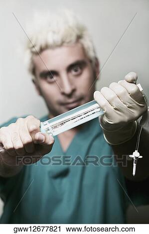 Portrait of a surgeon holding a syringe View Large Photo Image Stock Image - Portrait of a surgeon holding a syringe. Fotosearch