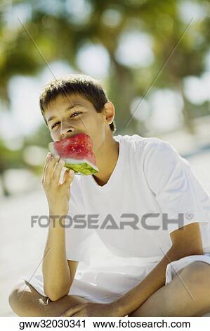 Portrait of a teenage boy eating a slice of watermelon View Large Photo Image Stock Image - Portrait of a teenage boy eating a slice of watermelon. Fotosearch
