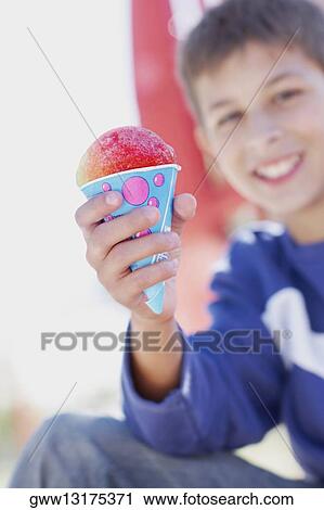 Stock Image - Portrait of a teenage boy smiling and holding an ice-cream cone. Fotosearch
