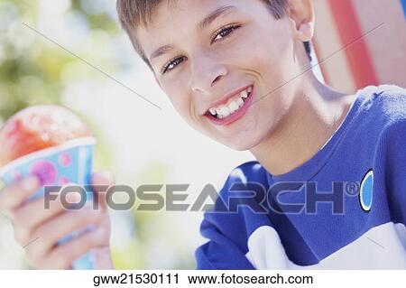 Stock Image - Portrait of a teenage boy smiling and holding an ice-cream cone. Fotosearch
