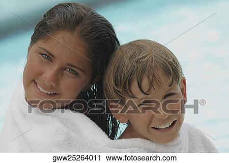 Stock Image - Portrait of a teenage girl and her brother wrapped in a towel and smiling. Fotosearch