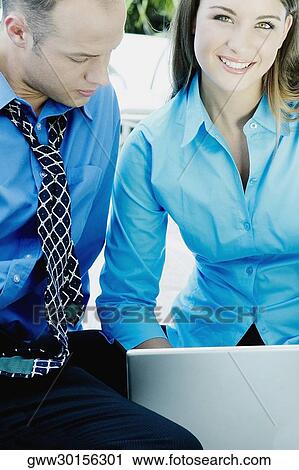 Portrait of a teenage girl using a laptop with a businessman sitting beside her View Large Photo Image Stock Image - Portrait of a teenage girl using a laptop with a businessman sitting beside her. Fotosearch