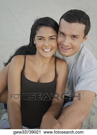 Portrait of a young couple sitting and smiling View Large Photo Image Stock Image - Portrait of a young couple sitting and smiling. Fotosearch